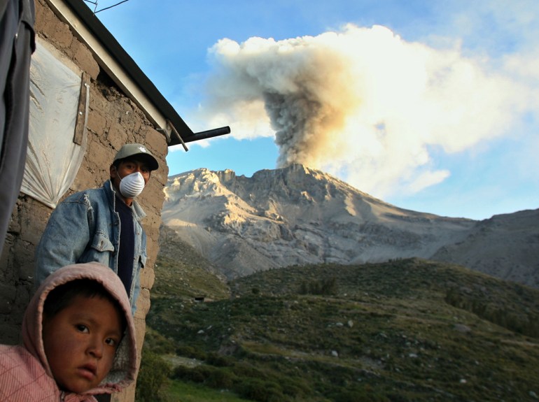Местный житель носит маску, чтобы защитить себя от пепла, извергающегося из перуанского вулкана Убинас.