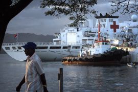 The Peace Ark Chinese hospital ship on a visit to Fiji in 2014. It is docked at port. A man is walking past on the shore.