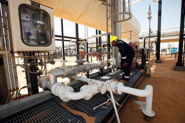 A worker checks pipes and valves at El Sharara oilfield