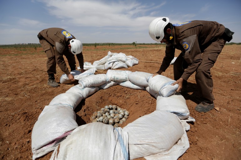 Anggota pertahanan sipil mengumpulkan bom tandan untuk meledakkannya dengan aman