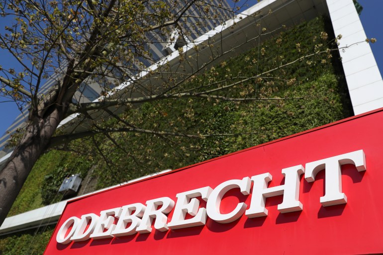 The exterior of a building shows the logo "Odebrecht." A tree grows nearby.