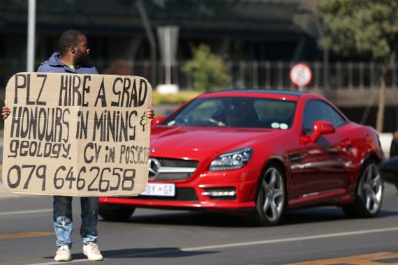 A man holds a placard looking for work in South Africa