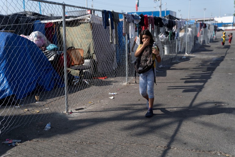Seorang gadis berjalan di luar kamp migran dekat perbatasan El Chaparral di Tijuana, Meksiko, 8 November 2021. 