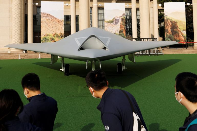 Visitors look at a display of GJ-11 stealth armed reconnaissance drone at an exhibition in Beijing