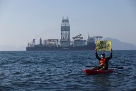 A Greenpeace activist holds a sign as he confronts the deep sea mining vessel Hidden Gem