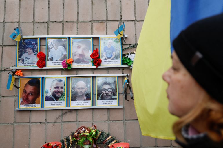 A woman looks at portraits of local men tortured and killed by Russian soldiers during occupation the Bucha town, on a day of the first anniversary of Russia's attack on Ukraine, at the place of their death at Yablunska street in Bucha, outside Kyiv, Ukraine February 24, 2023. REUTERS/Valentyn Ogirenko