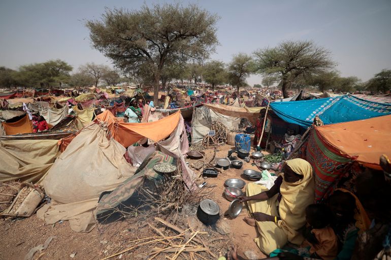 A Sudanese woman who fled the conflict in Sudan's Darfur region, and was previously internally displaced in Sudan, cooks, as she sits at her makeshift shelter near the border between Sudan and Chad, while taking refuge in Borota, Chad May 13, 2023
