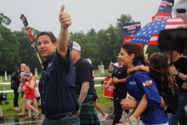 Ron DeSantis, walking with supporters and his wife Casey outside, flashes a thumbs up.