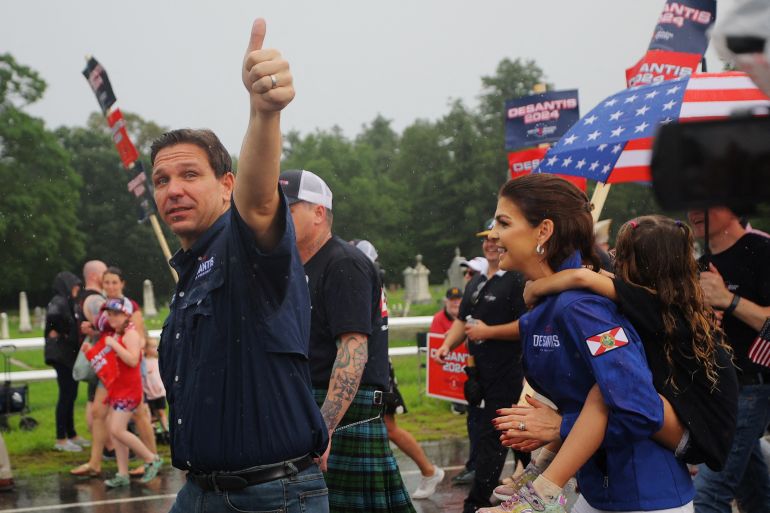 Ron DeSantis, walking with supporters and his wife Casey outside, flashes a thumbs up.