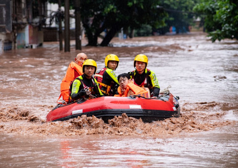 Rescue workers evacuate stranded residents on a flooded street after heavy rainfall in Wanzhou district of Chongqing