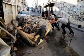 Palestinians try to move a damaged car after the Israeli army's withdrawal from the Jenin camp, in Jenin, in the Israeli-occupied West Bank