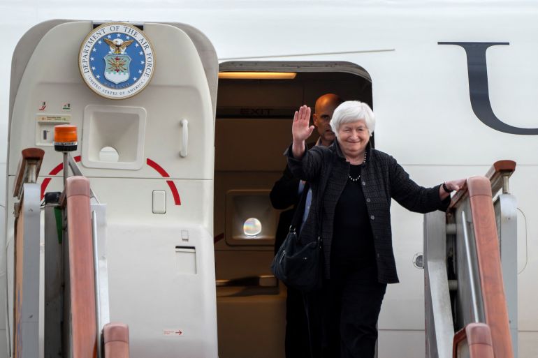 Janet Yellen waves as she exits a plane after landing in Beijing