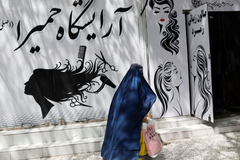 An Afghan woman walks past a beauty salon in Kabul, Afghanistan, July 6, 2023