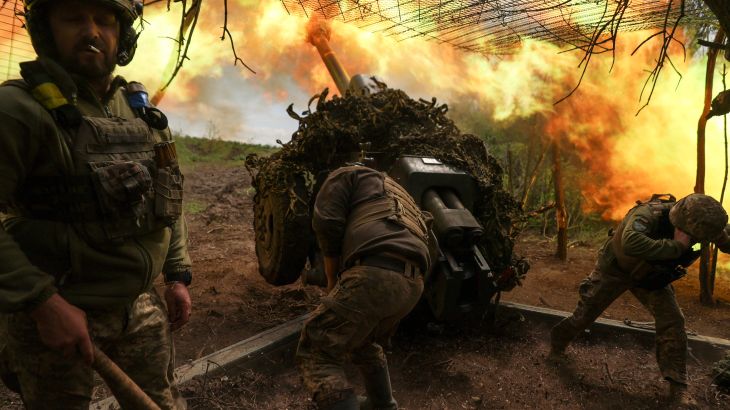 Ukrainian soldiers firing a howitzer gun towards Russian lines. There are lots of flames and smoke coming from the gun.