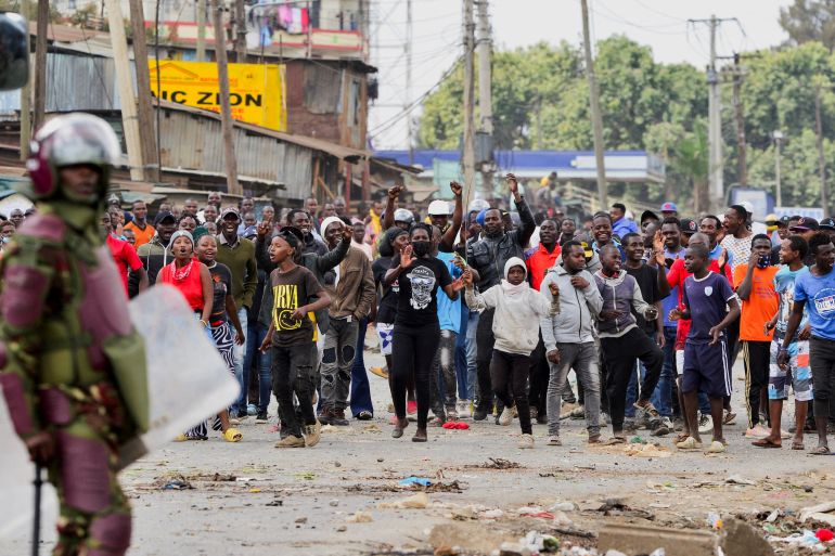 A riot police officer stands near supporters of Kenya's opposition leader Raila Odinga of the Azimio La Umoja (Declaration of Unity) One Kenya Alliance, during an anti-government protest against the imposition of tax hikes by the government, in Mathare settlement in Nairobi, Kenya, July 12, 2023.