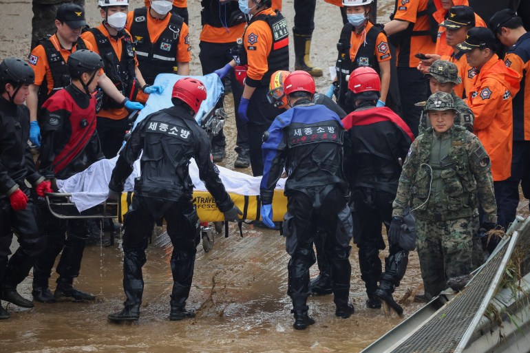I soccorritori trasportano il corpo di una vittima durante un'operazione di ricerca e soccorso nei pressi di un tunnel sommerso in un fiume allagato da forti piogge a Cheongju, in Corea del Sud, il 16 luglio 2023. 