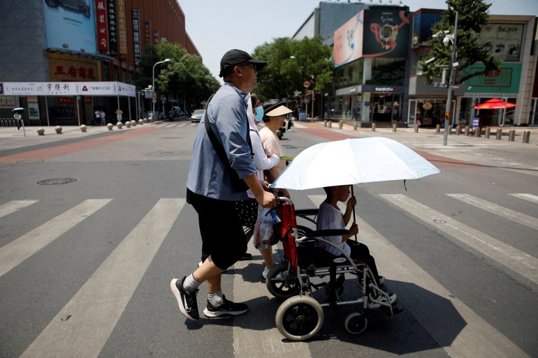 Pedestrians cross a road on a hot day amid an orange alert for heatwave, in Beijing, China June 16, 2023. REUTERS/Florence Lo/File Photo