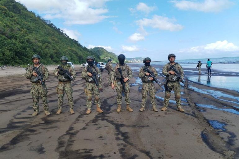 Soldiers stand guard at the site of an oil spill