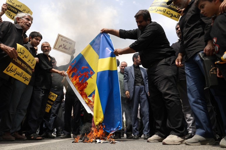 Demonstrators burn the Swedish flag during a protest against the insult to the Koran in Stockholm