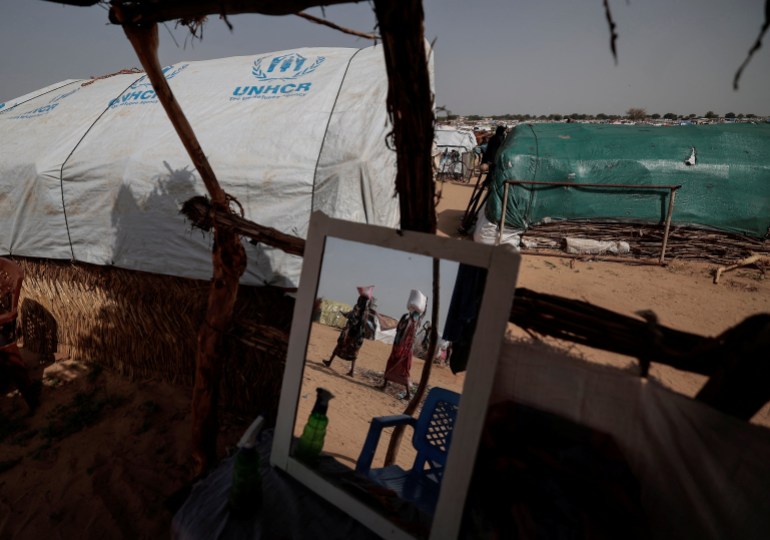 Las mujeres sudanesas que huyeron del conflicto en la región sudanesa de Darfur cargan sus provisiones de alimentos mientras caminan hacia sus refugios improvisados ​​en Adre, Chad.
