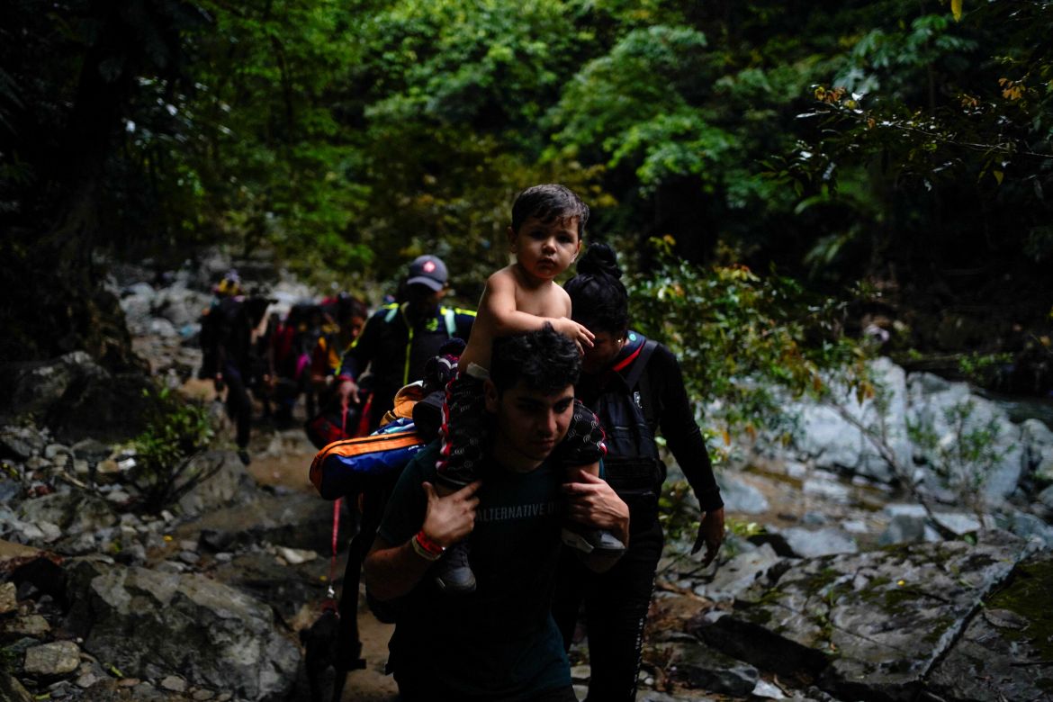 A Venezuelan migrant carries his son on his shoulders