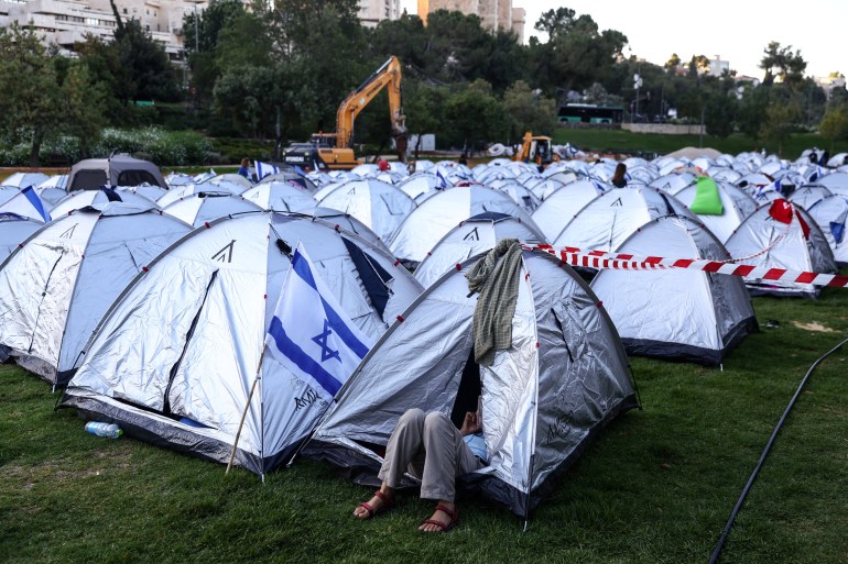 A protester against the Israeli government's judicial overhaul plans checks her phone inside a tent in a camp protesters erected in Jerusalem July 23