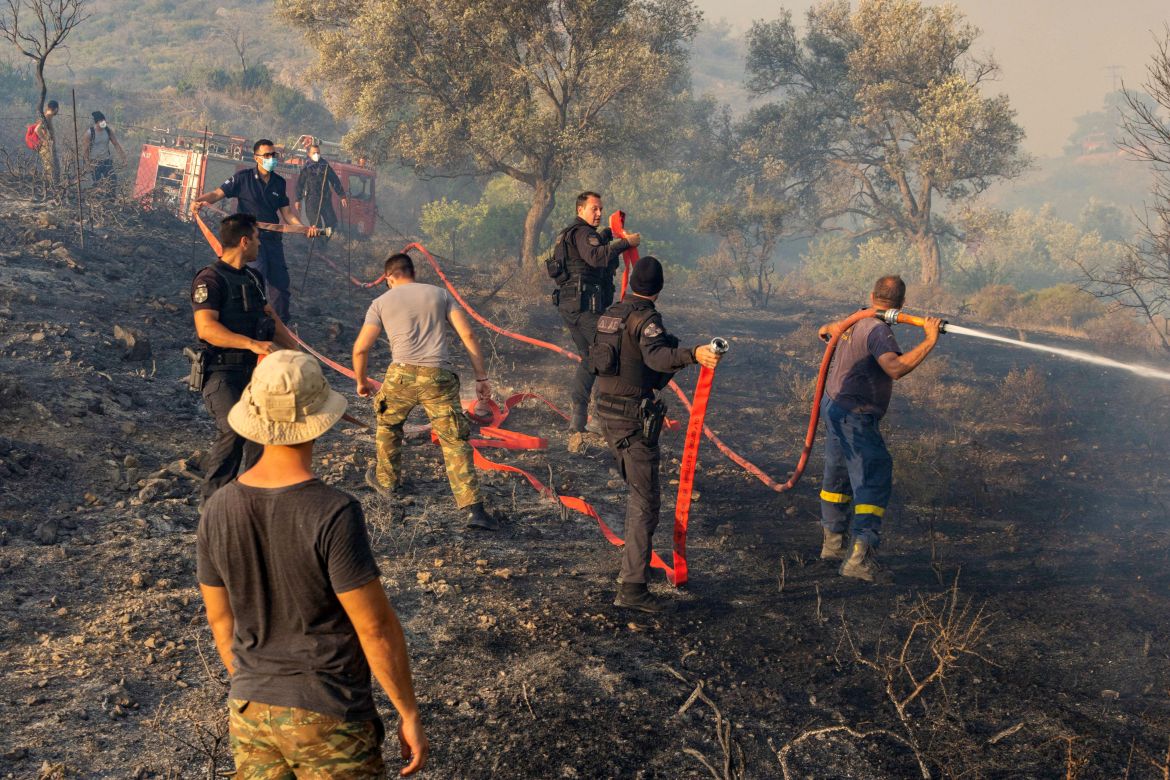 Firefighters, volunteers and police officers operate as a wildfire burns near the village of Asklipieio,