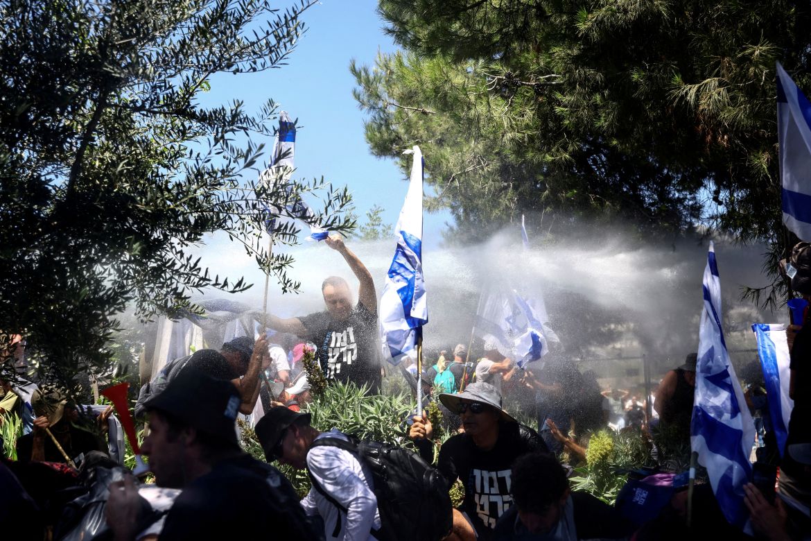 Protesters are sprayed by a police water cannon as they approach a police barrier during a demonstration against Israeli Prime Minister Benjamin Netanyahu