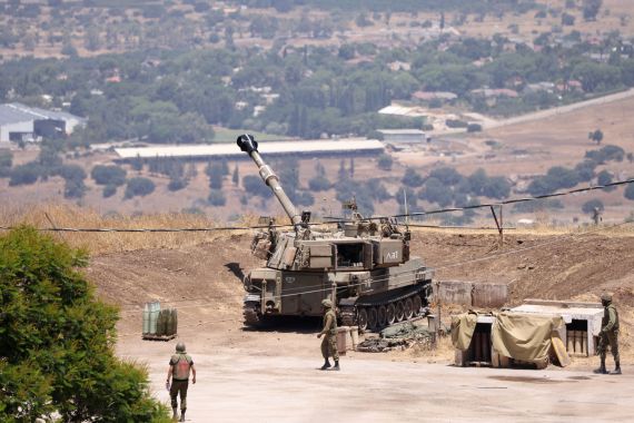 Israeli soldiers stand near an army self-propelled artillery vehicle on the outskirts of Kiryat Shmona near Israel's border with Lebanon