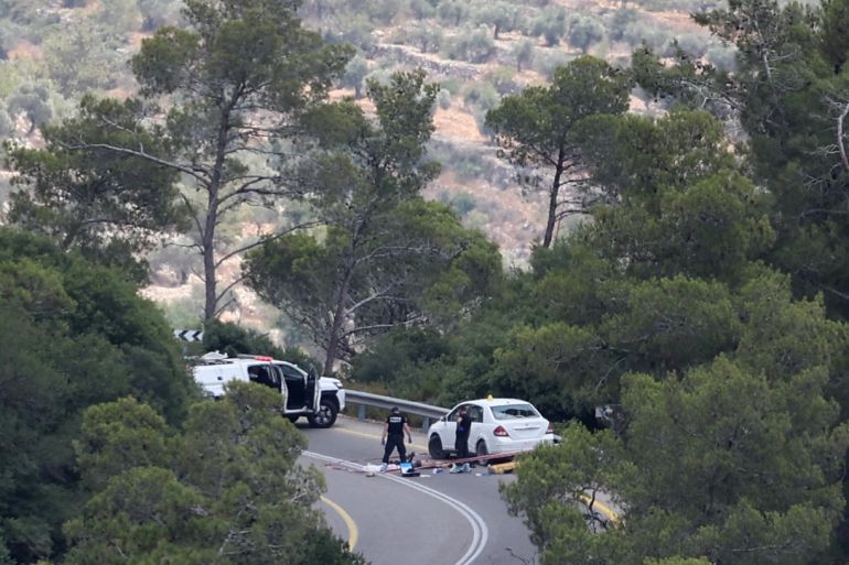 Israeli police gather around the body of a reported gunman, near the village of Deir Nidham