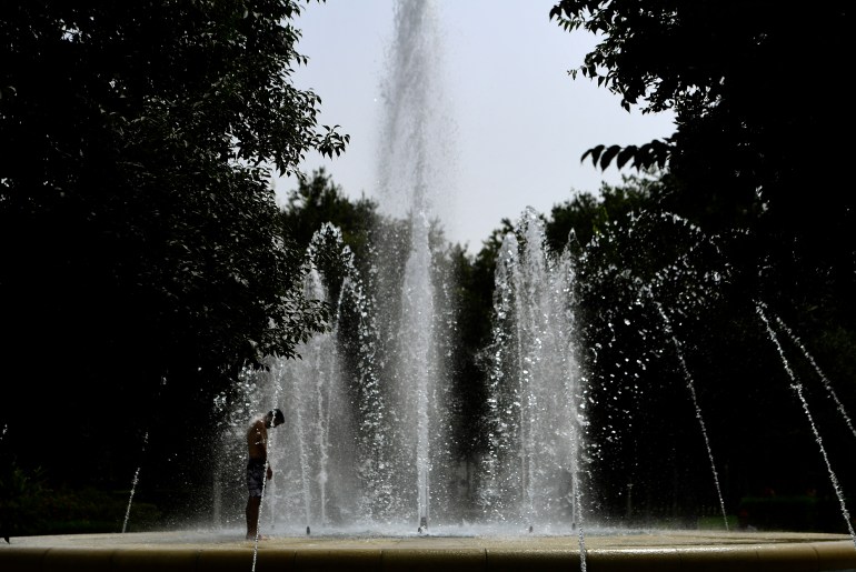 A man cools off by a fountain water during a heatwave in Seville on July 10, 2023. - Temperatures were soaring across Spain on July 10 with the mercury set to touch 44 degrees Celsius (111 Fahrenheit) in the south as the country braced for its second heatwave in a fortnight. (Photo by CRISTINA QUICLER / AFP)