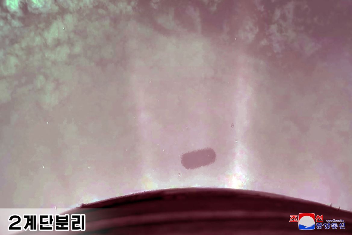 A blurry image showing the second stage separation of the ICBM. There is a small black cylindrical item in the bottom third of the photo and rays of light.