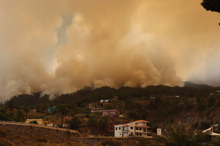 A picture taken on July 15, 2023 on the Spanish Canary Island of La Palma shows the evacuated town of Tijarafe surrounded by smoke billowing from wild fire near La Caldera de Taburiente National Park. - The 2.560 residents of Tijarafe have been evacuated and 2.000 hectares burnt after a wild fire started in the night of July 15 in Puntagorda, northwest of the island. During the last week, the Canary islands have experienced a heat wave that saw Spain's highest temperatures. (Photo by STRINGER / AFP)