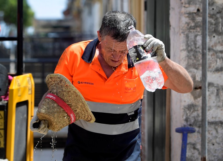 A worker cools off while working in a street during a heatwave in Sevilla, in the southern Spanish region of Andalusia, on July 17, 2023. - Scorching weather gripped three continents, whipping up wildfires and threatening to topple temperature records as the dire consequences of global warming take shape. Little reprieve is forecast for Spain, where the met agency warned of a new heatwave on July 17 through July 19 taking temperatures above 40C in the Canary Islands and the southern Andalusia region. (Photo by CRISTINA QUICLER / AFP)