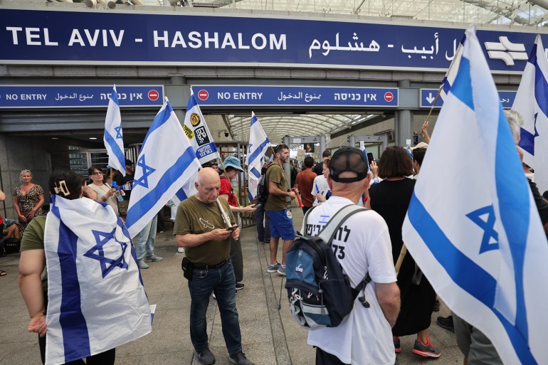 Demonstrators lift flags as they stage a 'day of resistance' to protest the Israeli government's judicial overhaul bill, at Tel Aviv HaShalom railway station on July 18, 2023. (Photo by JACK GUEZ / AFP)