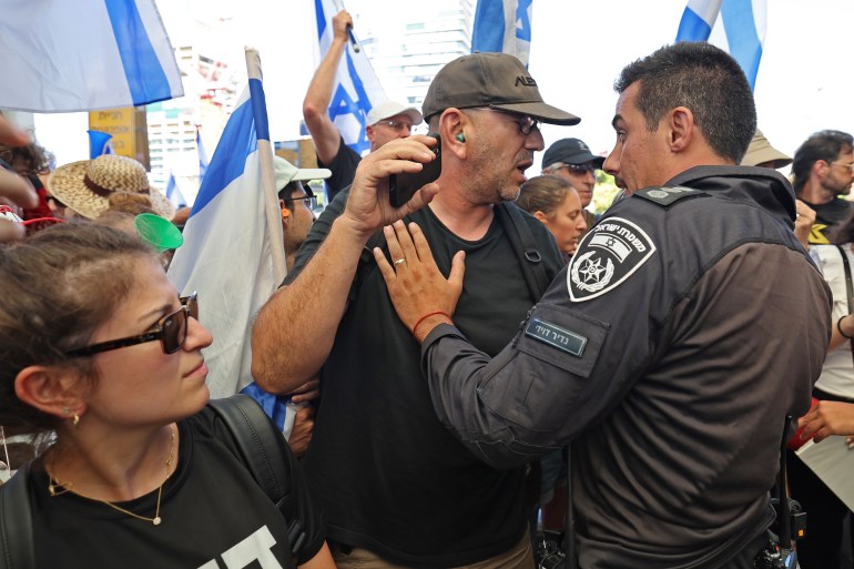 Seorang pengunjuk rasa bentrok dengan seorang polisi selama protes terhadap RUU perbaikan peradilan pemerintah Israel, di stasiun kereta Tel Aviv HaShalom pada 18 Juli 2023. (Foto oleh JACK GUEZ / AFP)
