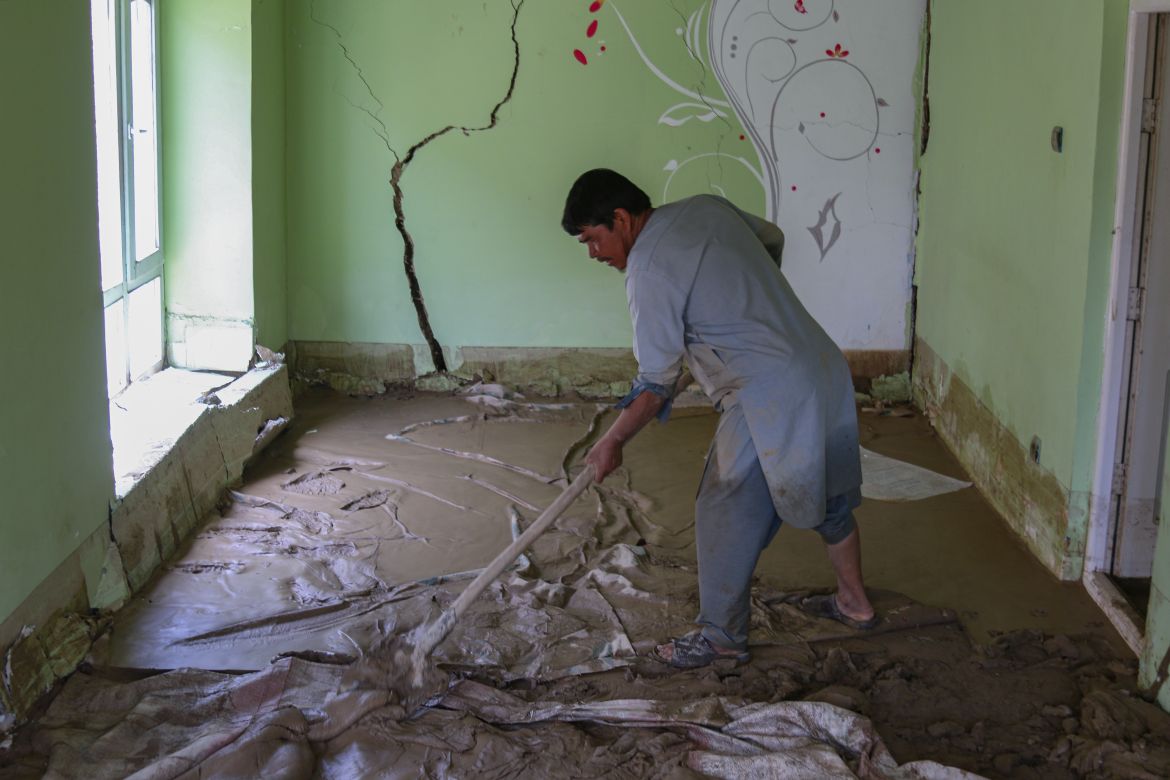 An Afghan man cleans debris and mud from his house following flash floods in the Khair Abad area in Ghazni province