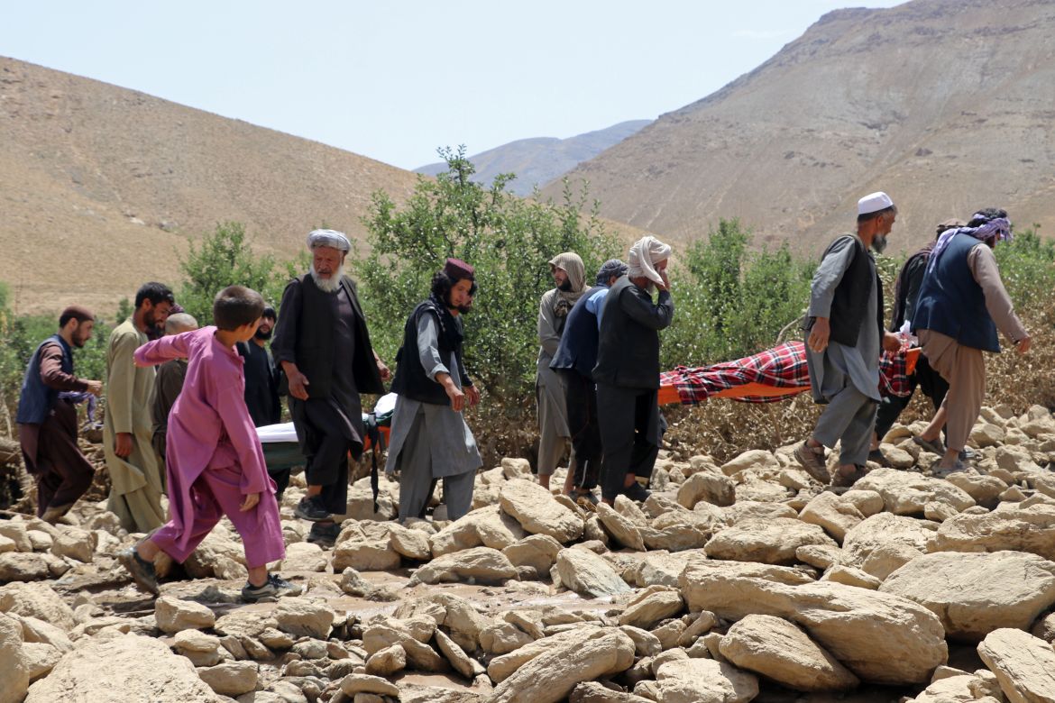 Afghan residents carry the bodies of victims, who died in flash floods in the Jalrez district