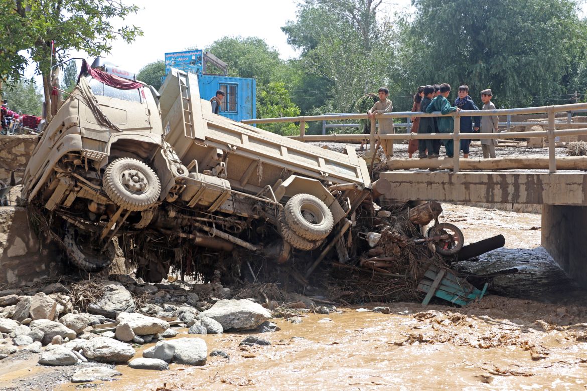 Afghan boys look at a truck that was damaged in flash floods