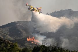 A fire fighting aircraft drops water over a wildfire close to village of Vati in the southern part of the Greek island of Rhodes