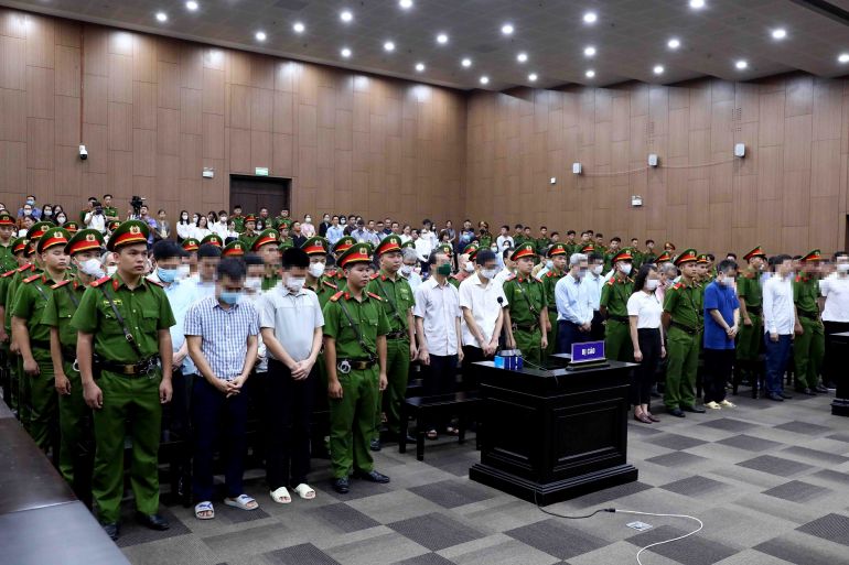 This picture taken and released by the Vietnam News Agency (VNA) on July 28, 2023 shows defendants (in civil shirts) standing for sentencing in a Hanoi courtroom for the repatriation flight trial. - A total of 54 officials and businesspeople were found guilty of receiving, offering or being the go-between for bribes, carrying out fraud and abusing positions of power, judges said in a verdict July 28. (Photo by Vietnam News Agency / Vietnam News Agency / AFP)