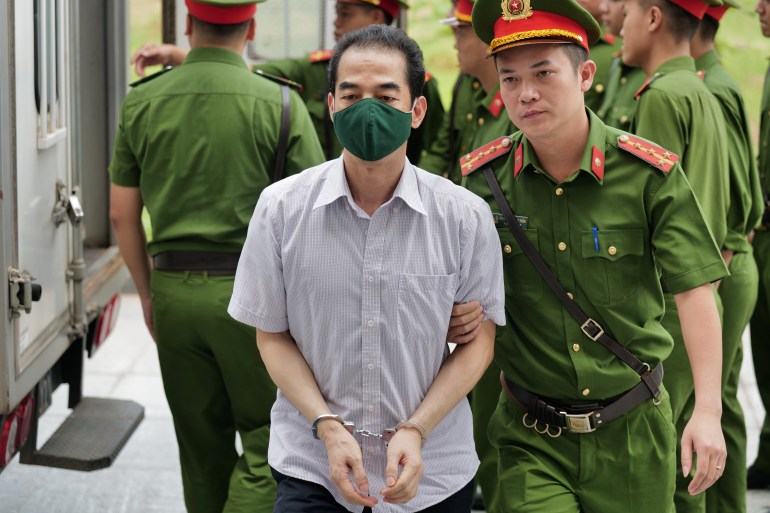 Vietnam's former deputy minister of foreign affairs To Anh Dung is led into court by police for sentencing during the repatriation flight trial in Hanoi on July 28, 2023. (Photo by Anh TUC / AFP)