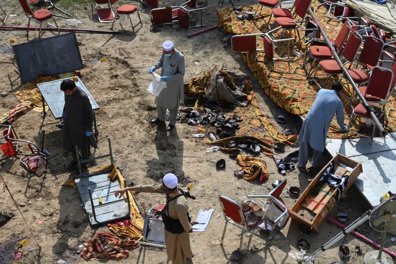 Police officials examine the site of a bomb blast in Bajaur district of Khyber-Pakhtunkhwa province on July 31, 2023. - At least 44 people were killed and more than 100 others wounded on July 30 by a suicide bombing at a political gathering of a leading Islamic party in northwest Pakistan, officials said. (Photo by Abdul MAJEED / AFP)