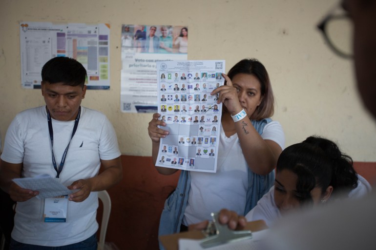 Seorang wanita memegang surat suara, di mana beberapa kandidat dicoret dengan X.