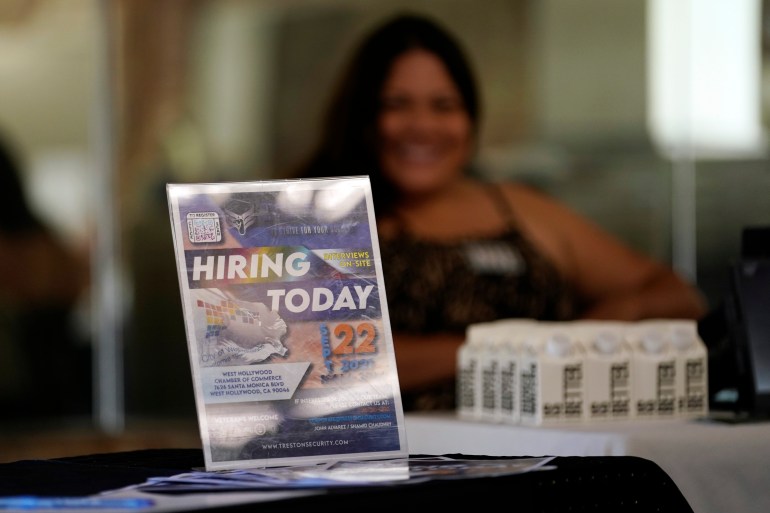 A hiring sign is placed at a booth for prospective employers during a job fair in LA, USA