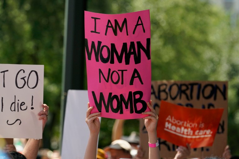 A woman holds a sign that says 'I am a woman, not a womb'
