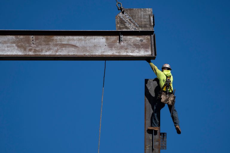 An ironworker guides a beam during construction of a municipal building in Norristown, Pennsylvania, US