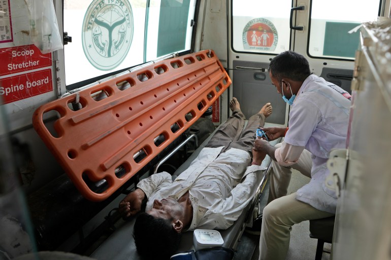 Jitendra Kumar, a paramedic checks the oxygen level of his patient who is suffering from a heat stroke after carrying him in an ambulance from his home in village Mirchwara, 24 kilometers (14.91 miles) from Banpur in Indian state of Uttar Pradesh, Saturday, June 17, 2023