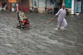 A man pulls a handcart carrying a boy amid floods in Pakistan
