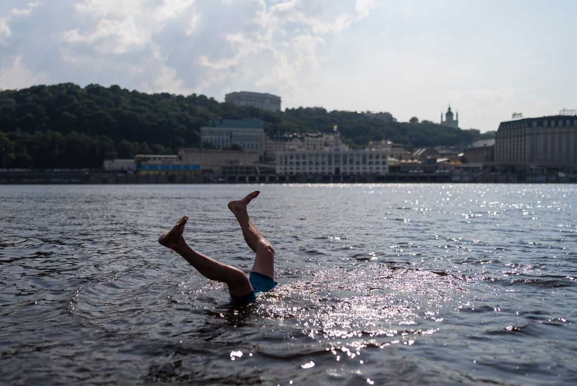 A man does a flip while cooling off in the Dnieper River in Kyiv,